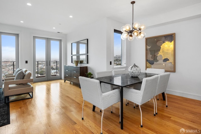 dining room featuring a wealth of natural light, light hardwood / wood-style flooring, french doors, and a notable chandelier