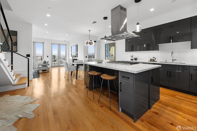 kitchen featuring sink, a center island, light hardwood / wood-style flooring, island exhaust hood, and decorative light fixtures