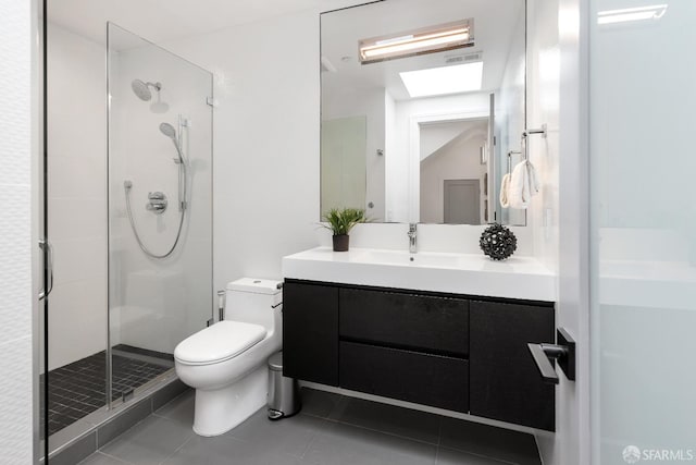 bathroom with vanity, tile patterned floors, a skylight, toilet, and a shower with shower door