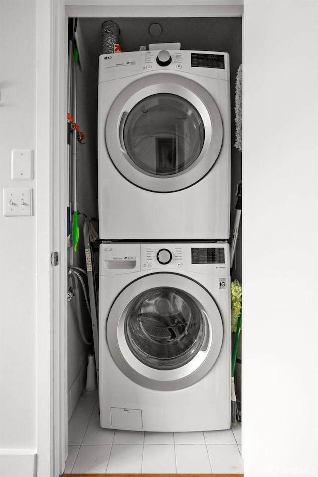 laundry area featuring light tile patterned floors and stacked washer and dryer