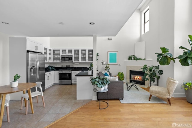 kitchen with white cabinets, light tile patterned floors, a high end fireplace, and appliances with stainless steel finishes