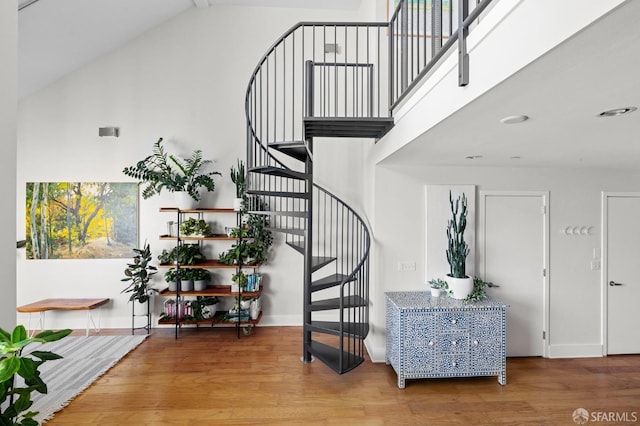 stairs with hardwood / wood-style floors and a towering ceiling