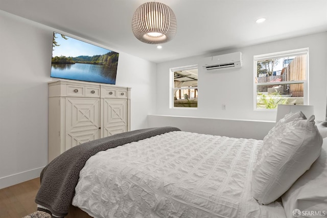 bedroom with a wall mounted AC, wood finished floors, recessed lighting, and baseboards