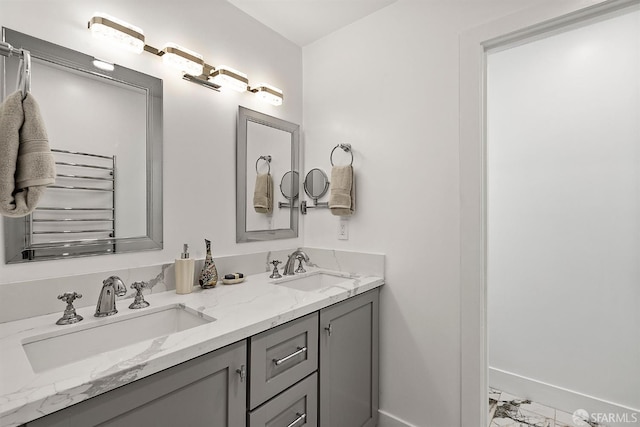 bathroom with marble finish flooring, baseboards, and double vanity