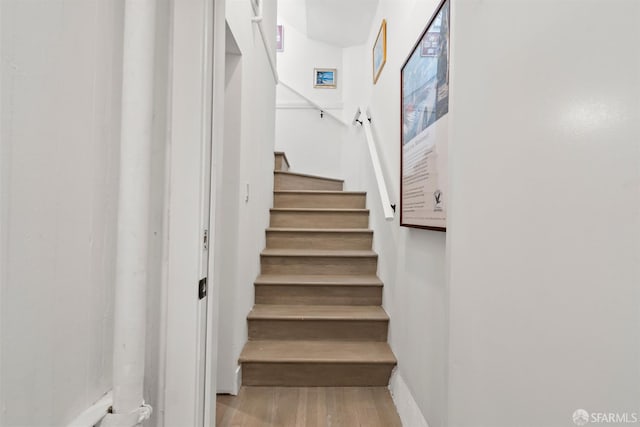staircase featuring wood finished floors and baseboards