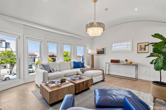 living area with plenty of natural light, lofted ceiling, baseboards, and light wood-style floors