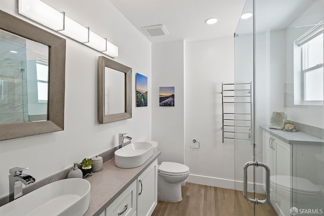 full bathroom with toilet, wood finished floors, a shower stall, double vanity, and recessed lighting