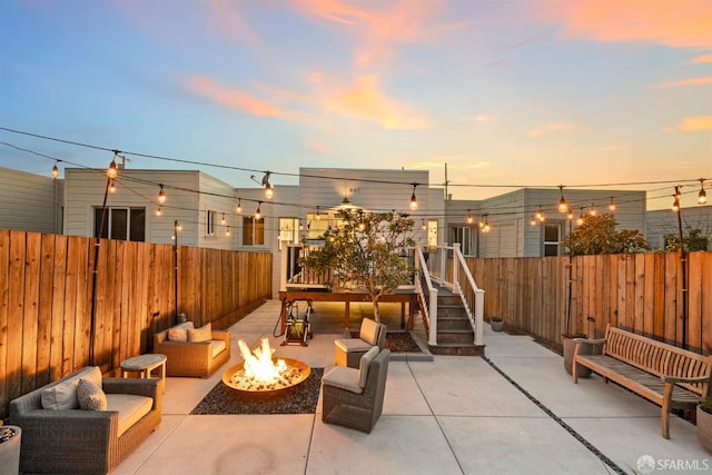 view of patio featuring a fenced backyard, a wooden deck, and an outdoor living space with a fire pit