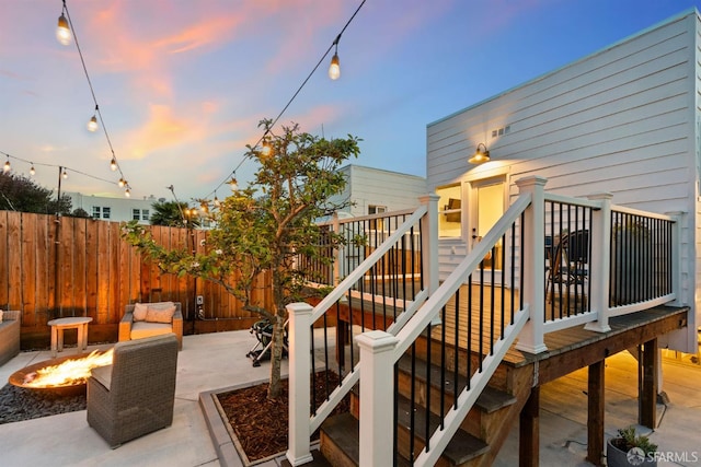 wooden deck featuring a fire pit, stairway, a patio, and fence