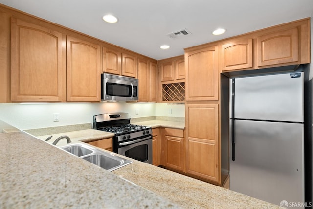 kitchen featuring appliances with stainless steel finishes, sink, and light stone counters