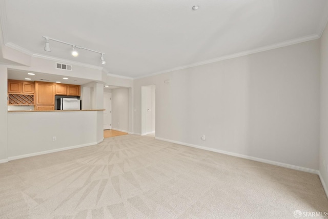 unfurnished living room featuring crown molding, light colored carpet, and rail lighting