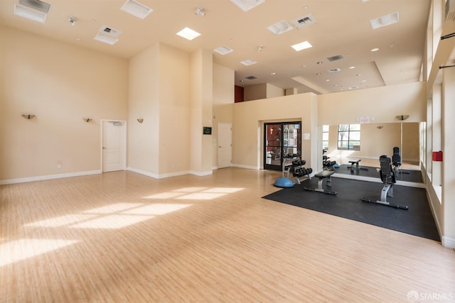 exercise room featuring light wood-type flooring and a high ceiling