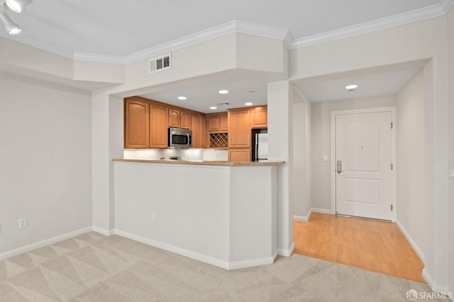 kitchen with light carpet, crown molding, kitchen peninsula, and appliances with stainless steel finishes