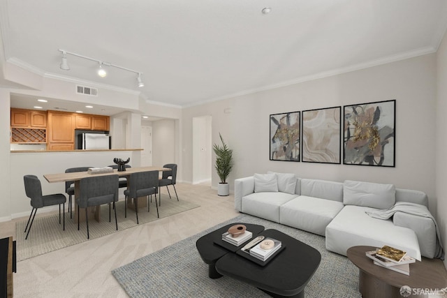 carpeted living room featuring ornamental molding and rail lighting