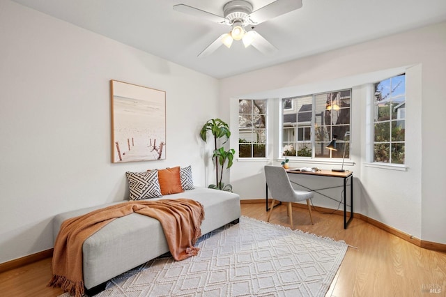 sitting room with wood finished floors, a ceiling fan, and baseboards