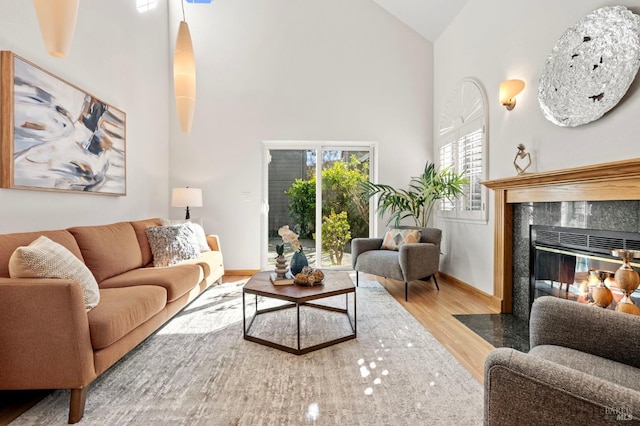 living room with baseboards, a fireplace, high vaulted ceiling, and wood finished floors