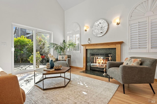 living area featuring high vaulted ceiling, wood finished floors, and a high end fireplace