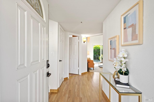 hall featuring light wood-style flooring and baseboards