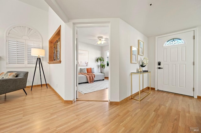 entryway featuring baseboards, a ceiling fan, and light wood-style floors