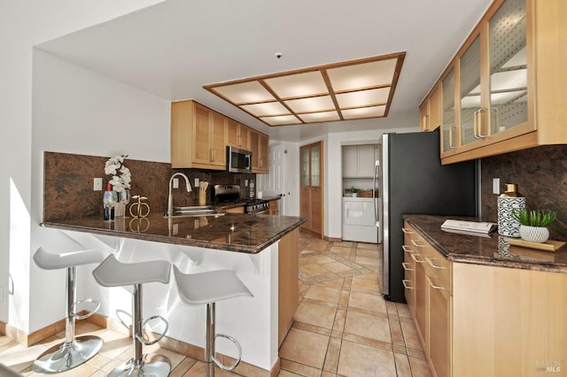 kitchen featuring decorative backsplash, appliances with stainless steel finishes, glass insert cabinets, a sink, and a peninsula