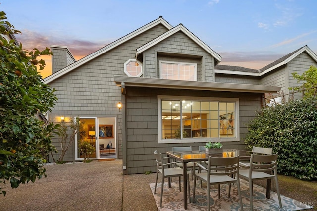 back of property at dusk with a patio area and outdoor dining space