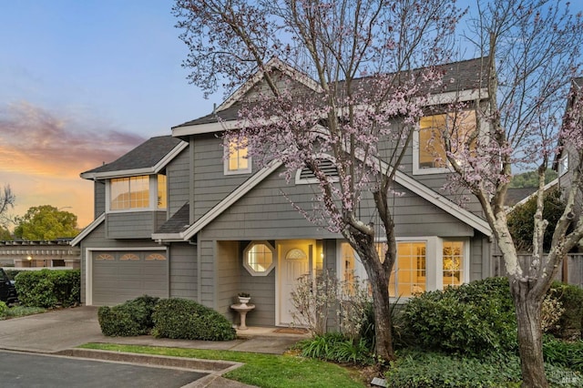 view of front facade featuring a garage, driveway, and a shingled roof