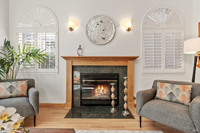 sitting room with a high end fireplace, baseboards, and wood finished floors