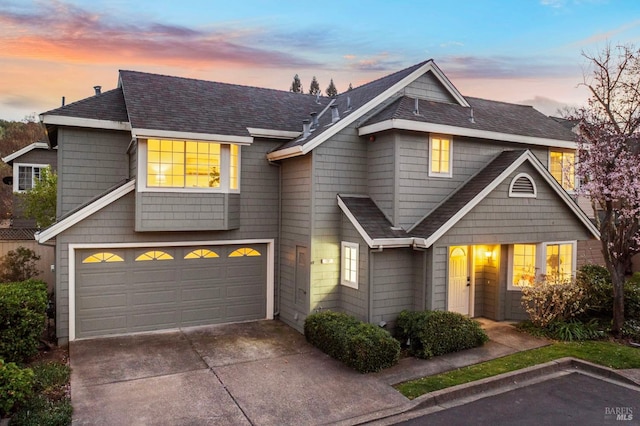 view of front facade featuring a garage, driveway, and roof with shingles