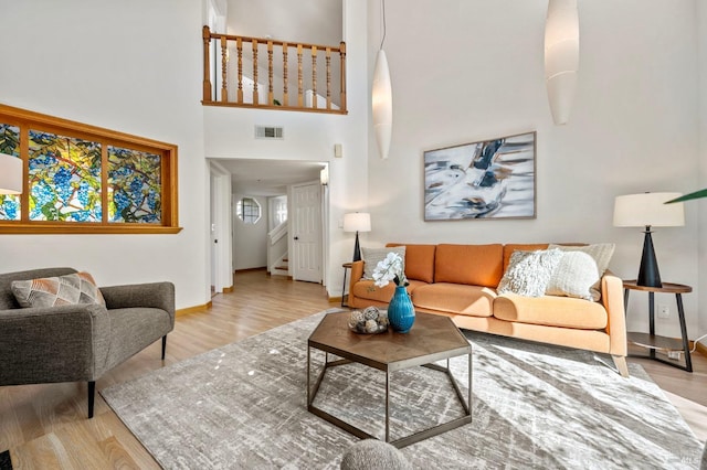 living room featuring stairs, wood finished floors, visible vents, and baseboards