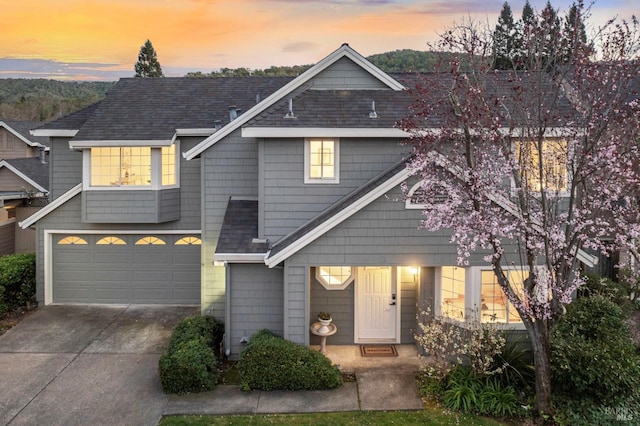 townhome / multi-family property with a shingled roof, concrete driveway, and an attached garage