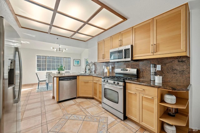 kitchen with light brown cabinets, stainless steel appliances, a peninsula, a sink, and decorative backsplash