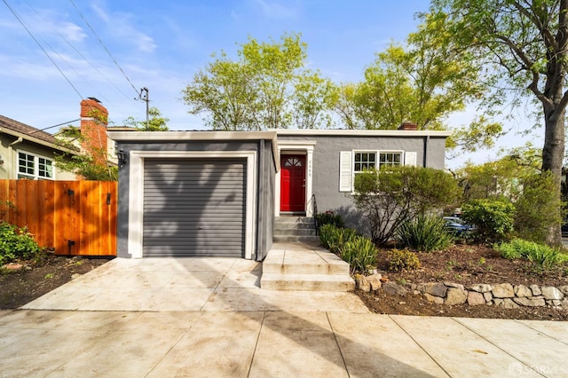 view of front of house with driveway, an attached garage, fence, and stucco siding