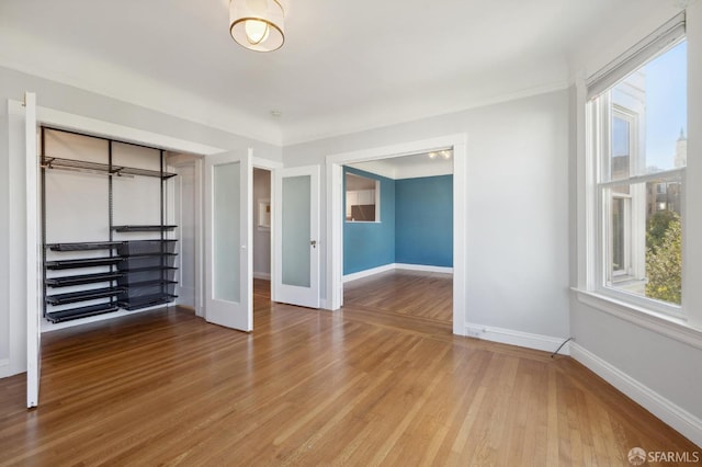 unfurnished bedroom featuring multiple windows and wood-type flooring