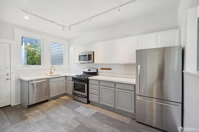 kitchen with gray cabinets, appliances with stainless steel finishes, sink, and rail lighting