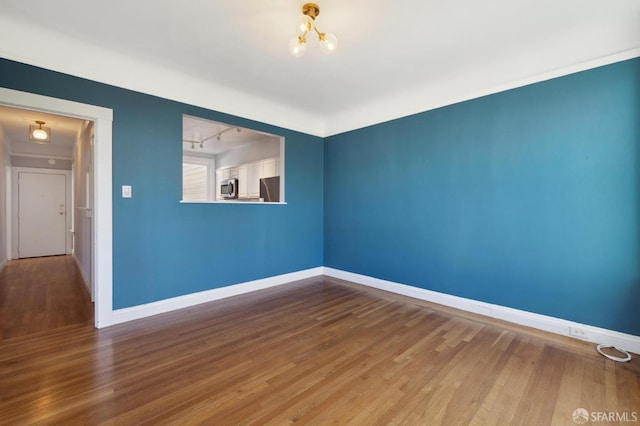 spare room featuring wood-type flooring and a notable chandelier