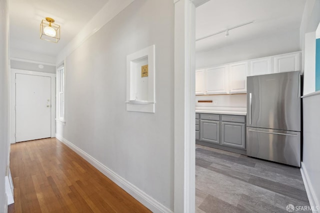 corridor with rail lighting and light hardwood / wood-style flooring