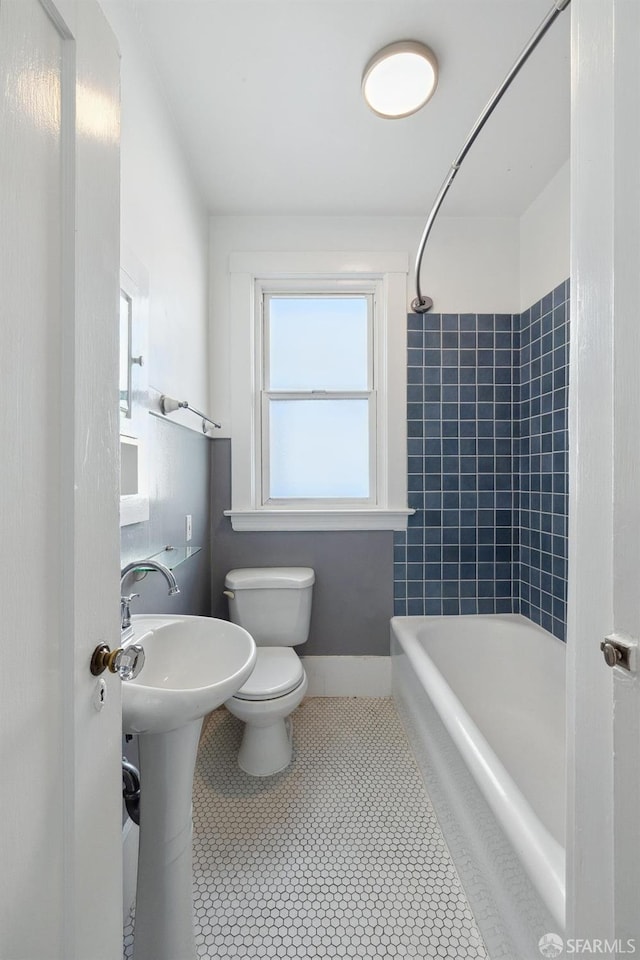 bathroom with tile patterned flooring, tiled shower / bath, and toilet