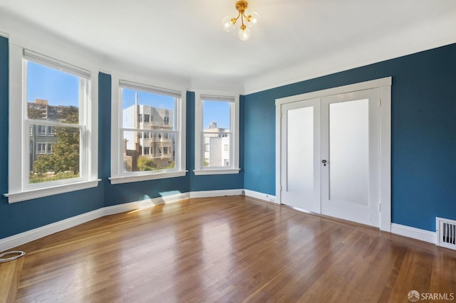 empty room with a notable chandelier and hardwood / wood-style flooring