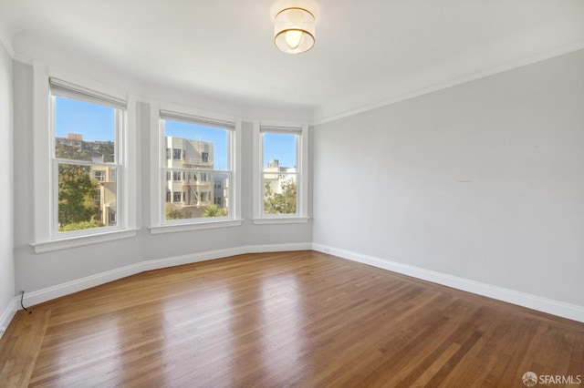 empty room with wood-type flooring and crown molding