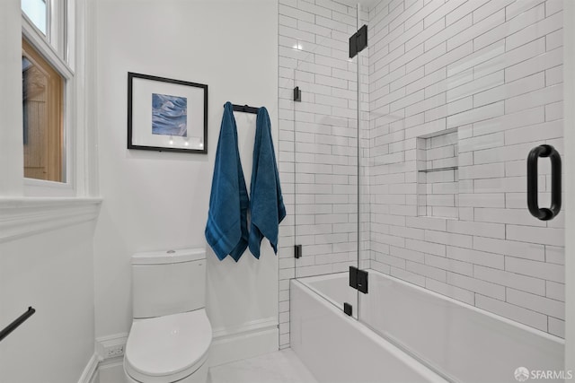 bathroom featuring combined bath / shower with glass door and toilet