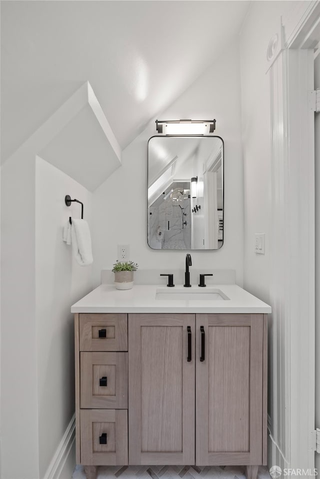 bathroom featuring vanity, a shower with door, and lofted ceiling