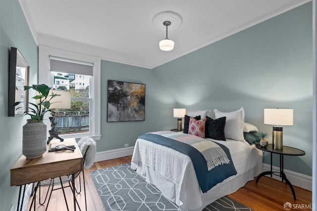 bedroom with hardwood / wood-style floors, ornamental molding, and vaulted ceiling