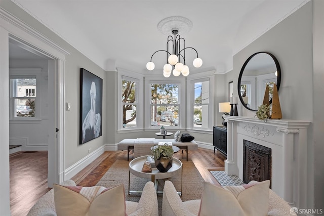 interior space with wood-type flooring, crown molding, a notable chandelier, and a fireplace