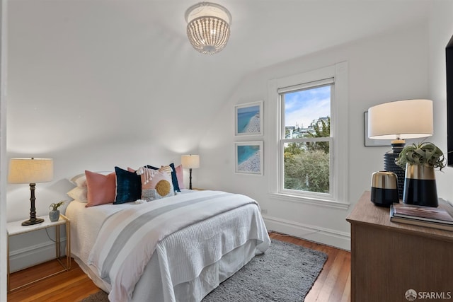 bedroom featuring hardwood / wood-style floors, a chandelier, and vaulted ceiling