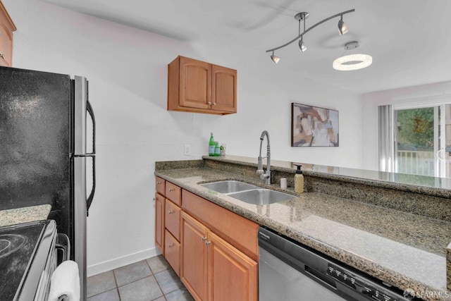 kitchen with rail lighting, sink, light tile patterned floors, appliances with stainless steel finishes, and stone counters