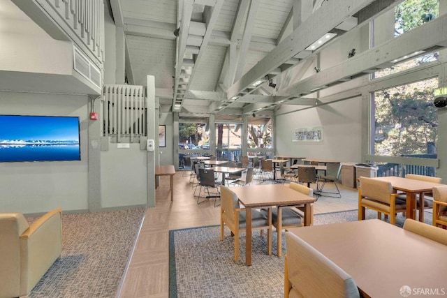 dining room featuring beamed ceiling, a high ceiling, a healthy amount of sunlight, and parquet floors