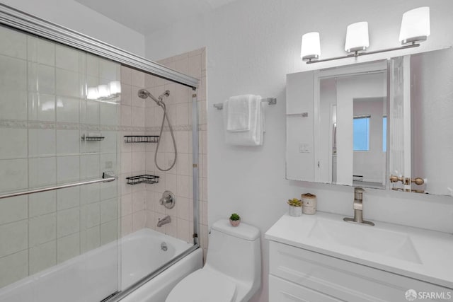 full bathroom featuring vanity, combined bath / shower with glass door, and toilet