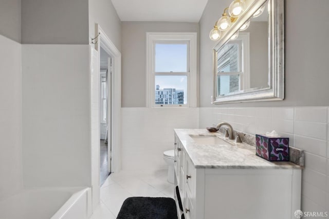 bathroom with tile patterned floors, vanity, tile walls, toilet, and a tub