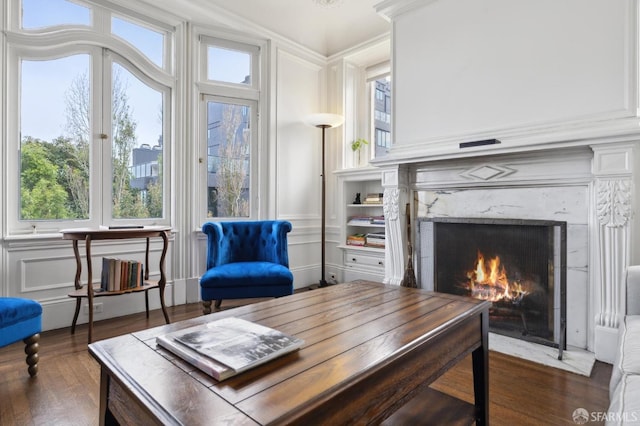 living area featuring crown molding, a fireplace, and dark wood-type flooring