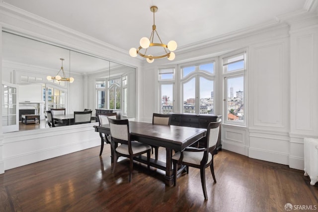 dining area featuring radiator heating unit, dark wood-type flooring, a chandelier, and ornamental molding